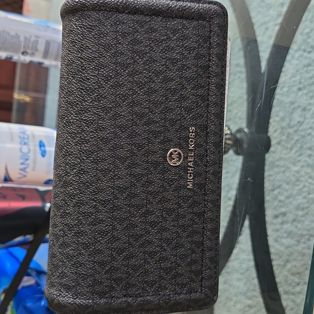 Small black and white crossbody purse with cell phone holder on back.